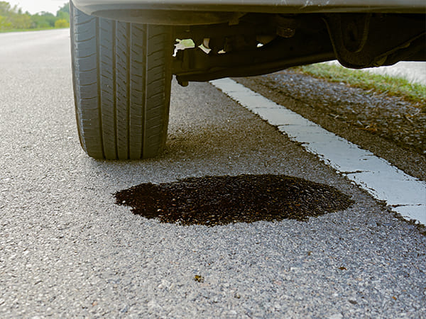 Oil puddle under vehicle showing potential Ford oil leak causes and repair concerns